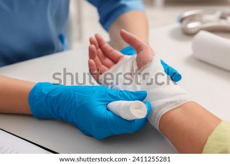 Doctor bandaging patient's burned hand indoors, closeup