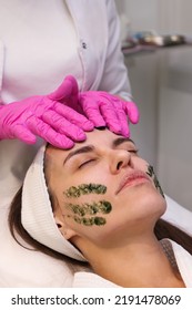 
Doctor Beautician Preparing Patient For LED Phototherapy For The Face. Cosmetologist Applying Green Gel With Seaweed Photosensitizer. Facial Care. Light Therapy In Clinic, Anti-age Procedure.