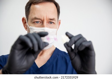 doctor in black gloves and white mask holds stained histology slide which is ready for microscopic examination. Cytology. The eyes in focus
