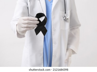 Doctor with black ribbon on light background. Melanoma concept - Powered by Shutterstock