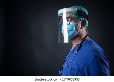 Doctor In Blue Coat With Protections And Face Shield Isolated On Black Background