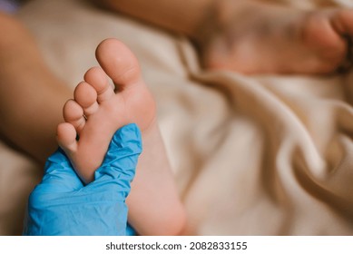 Doctor in blue gloves examines children's feet for the presence of diseases, fungus, flat feet. Selective focus. - Shutterstock ID 2082833155