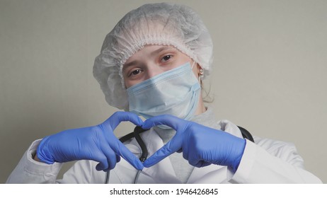 A Doctor In A Blue Mask And Gloves Smiles And Shows His Heart, A Professional Cardiologist In A Health Clinic, An Appointment With A Pediatrician In The Office, A Good Nurse, Coronavirus Pandemic