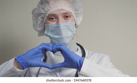 A Doctor In A Blue Mask And Gloves Smiles And Shows His Heart, A Professional Cardiologist In A Health Clinic, An Appointment With A Pediatrician In The Office, A Good Nurse, Coronavirus Pandemic