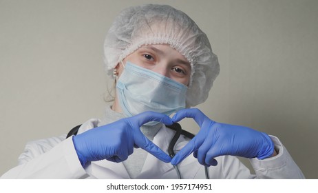 A Doctor In A Blue Mask And Gloves Smiles And Shows His Heart, A Professional Cardiologist In A Health Clinic, An Appointment With A Pediatrician In The Office, A Good Nurse, Coronavirus Pandemic