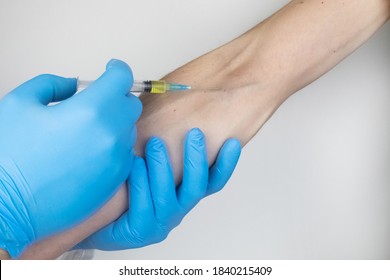 A Doctor In Blue Medical Gloves Makes An Injection Into A Vein. Intravenous Drug Administration. The Concept Of Providing Professional Medical Care