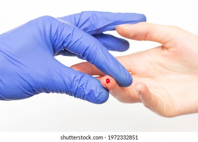 Doctor in blue medical gloves takes blood from the patient's finger on a white background, close-up. The concept of taking blood for glucose and hemoglobin, plasma