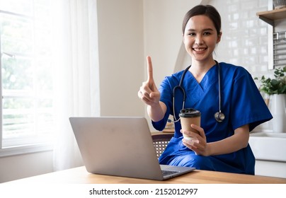 Doctor In Blue Scrubs Relaxing With Her Laptop On Coffee Break. Service Mind And Number One Stop Service