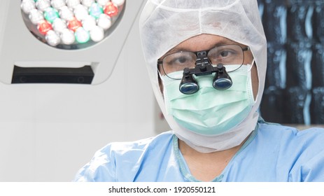 Doctor In Blue Surgical Gown Suit Working Inside Modern Operating Room.Surgeon Wearing Surgical Loupe Magnify Glasses For Advance Plastic And Cosmetic Surgery.Selective Focus.
Operating Room.