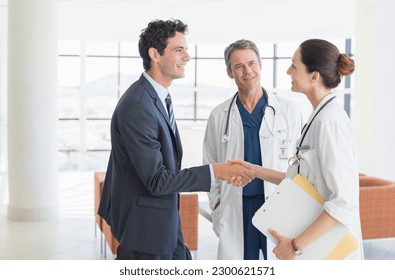 Doctor and businessman handshaking in hospital lobby - Powered by Shutterstock