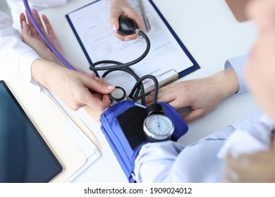 Doctor cardiologist measuring blood pressure to patient with tonometer. Diagnosis of arterial hypertension concept