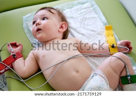 Doctor cardiologist pediatrician makes an electrocardiogram toddler baby boy. Doctor doing ecg to child checking heart health. Kid age one year (12 months)