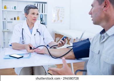 Doctor checking blood pressure of her patient in medical office
