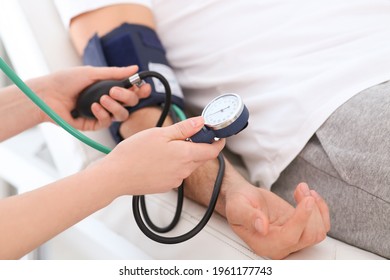 Doctor Checking Blood Pressure Of Man In Clinic, Closeup