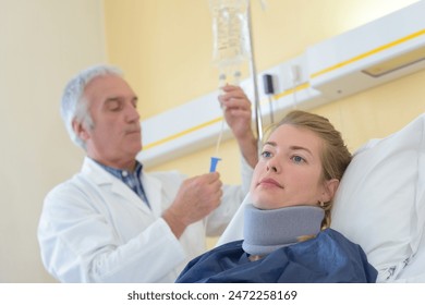 Doctor checking drip bag of patient wearing neck brace - Powered by Shutterstock