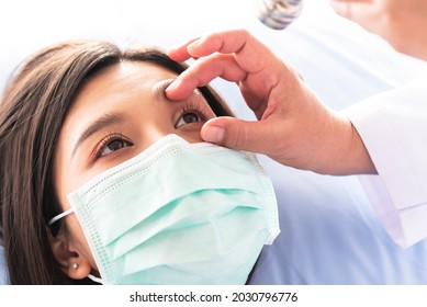 Doctor Checking The Eyes Of A Woman Patient, Which Wearing A Surgical Mask, To People Health Care And Cataract Disease Concept.