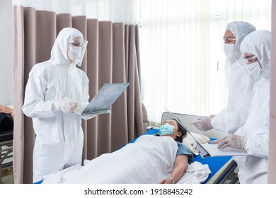 Doctor Checking Up The History Of The Disease Patient Lying In Bed. Doctors And Staff To Prevent COVID 19 Checking And Treating Patients In A Controlled Area, State Quarantine.