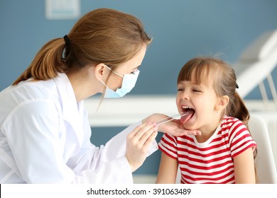 Doctor checking little girl's throat in the office - Powered by Shutterstock