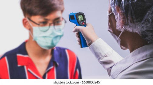 A Doctor checking a  Man's temperature with a censor thermometer check process before being accessed to the building, to prevent the covid19 virus 