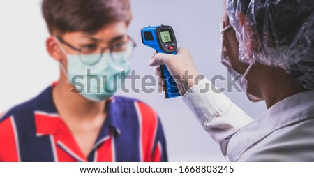 A Doctor checking a  Man's temperature with a censor thermometer check process before being accessed to the building, to prevent the covid19 virus 