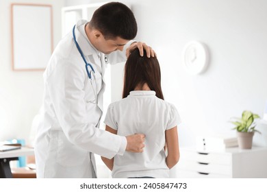 Doctor checking posture of little girl in clinic - Powered by Shutterstock