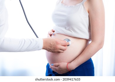 Doctor checking pregnant woman in the office, listening to heartbeat with a stethoscope. Treatment in perinatal time.