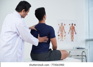 Doctor checking spine of a young man within the annual medical examination