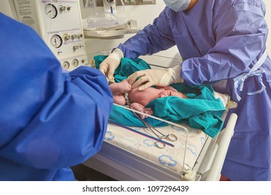 Doctor checking temperature of newborn baby in hospital background
