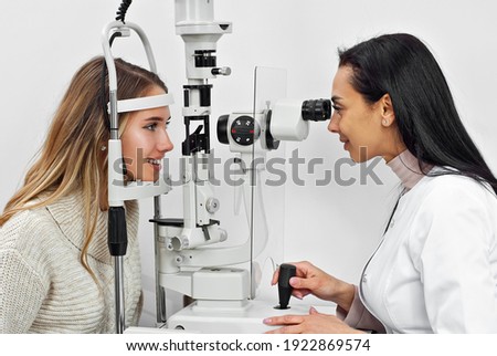 The doctor checks the patient's throat. Consultant in the ophthalmology office. Apparatus for checking vision on a white wall background.