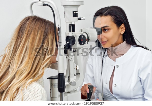 The doctor checks the patient\'s throat.\
Consultant in the ophthalmology office. Apparatus for checking\
vision on a white wall\
background.