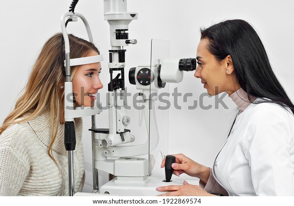 The doctor checks the patient\'s throat.\
Consultant in the ophthalmology office. Apparatus for checking\
vision on a white wall\
background.