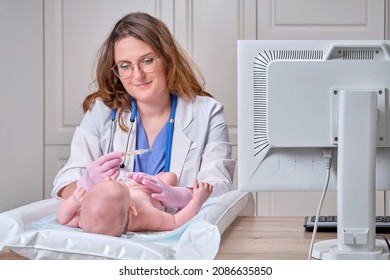 Doctor Checks The Temperature Of The Newborn Baby With A Thermometer. A Nurse In Uniform Measures The Child Fever With A Thermometer