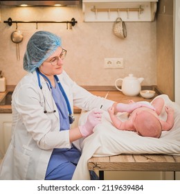 Doctor Checks The Temperature Of The Newborn Baby With A Thermometer. A Nurse In Uniform Measures The Child Fever With A Thermometer