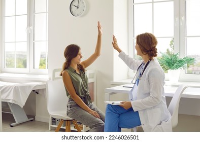 Doctor and child having fun during a medical checkup at the hospital. Friendly physician and a happy teen school girl smile and give each other a high five. Medicine, care, support, trust concept - Powered by Shutterstock