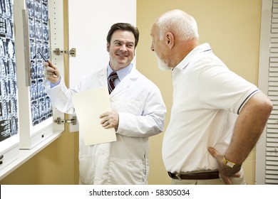 Doctor Or Chiropractor Explaining The Results Of A CT Scan Of The Spine To His Patient Suffering With Low Back Pain.