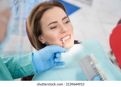 Doctor choosing color of woman teeth before dental treatment - Shutterstock ID 2139644915