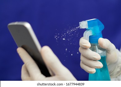 Doctor Cleaning Mobile Phone To Eliminate Covid-19 - Nurse Hands With Gloves Cleaning The Phone By Liquid Sanitizer At Hospital - Alcohol To Wipe Contaminating With Coronavirus