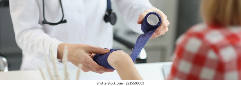 A Doctor In Clinic Bandages Woman's Wrist With An Elastic Band