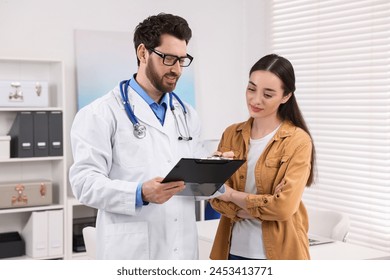 Doctor with clipboard consulting patient during appointment in clinic - Powered by Shutterstock