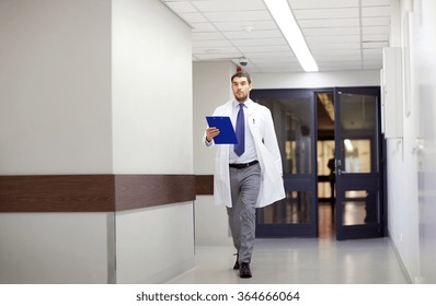 Doctor With Clipboard Walking Along Hospital