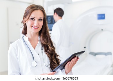 Doctor With Colleagues Standing In Hospital At CT Machine With Scan Results