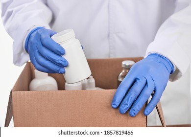 Doctor Collecting Prescribed Medicines Into A Cardboard Box. Specialist Wearing Latex Gloves For Safety. Drug Delivery Concept.