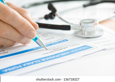 Doctor Completing A Medical Insurance Claim Form By Stethoscope 