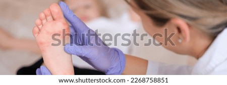 Doctor conducts medical examination of leg of child with red itchy rash closeup