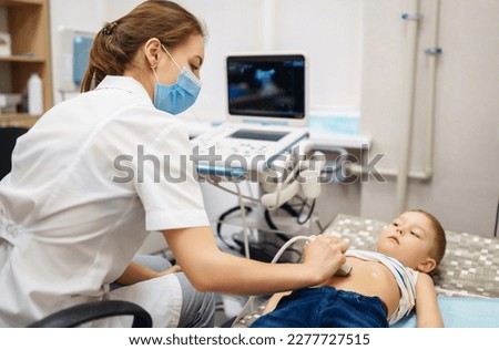 Doctor conducts an ultrasound examination of the heart and abdominal organs of a little boy using modern medical equipment in a clinic. Pediatrics and child development monitoring.