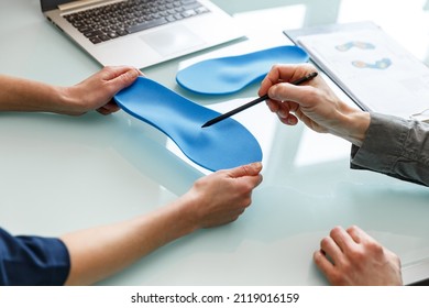 Doctor consulting patient on custom orthotic insoles in a clinic for a personalised custom fit. Feet recreation medicine concept - Shutterstock ID 2119016159