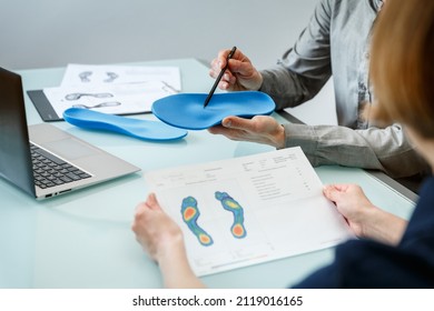 Doctor consulting patient on custom orthotic insoles in a clinic for a personalised custom fit. Feet recreation medicine concept - Shutterstock ID 2119016165