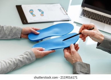 Doctor consulting patient on custom orthotic insoles in a clinic for a personalised custom fit. Feet recreation medicine concept - Shutterstock ID 2119016171