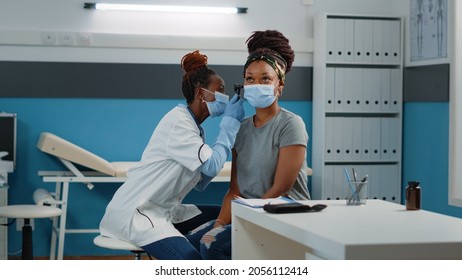 Doctor Consulting Patient With Otoscope For Ear Examination At Annual Checkup Visit. Otologist Doing Consultation With Medical Tool, Checking For Infection And Diagnosis On Woman.