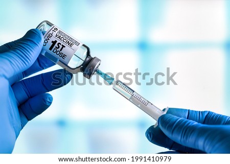 Doctor with Coronavirus vaccine bottle with the name of the 1st dose of vaccine on the label. Doctor preparing a dose for a patient of the first vaccine for Covid-19